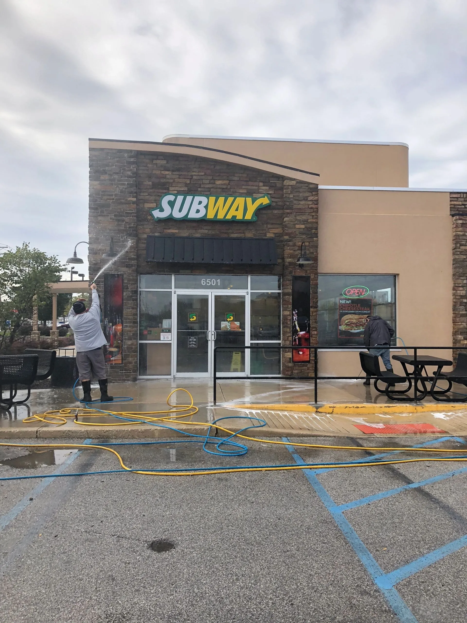 Crew member washing a restaurant storefront